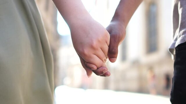 Unrecognizable black man and white woman hold each others hands. Close portrait, black and white hand. Interracial couple, love against racism