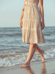 Woman wearing ethnic dress. Carefree boho girl in white summer dress walking on beach. Happy young woman relaxing on seashore. Summer vacation. Mindfulness and relaxation. Lifestyle