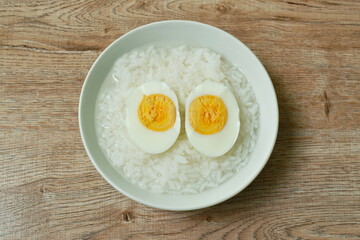 boiled egg half cut topping rice porridge in bowl on table