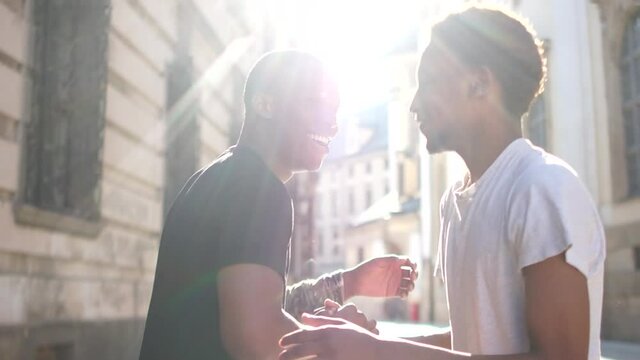 Two black guys greet each other at a meeting. Outdoor portrait African students greeting and hugging, sun glare. Brotherhood and Equality Concept