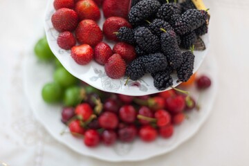 Nicely decorated fresh fruits on the two layered plate. Cherry, plum, Strawberry and black mulberry on the Turkish ceramic plate with two flors. Upper layer is in focus only.