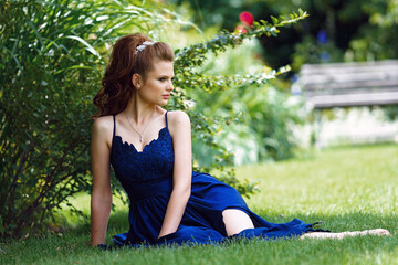 Naklejka na ściany i meble beautiful girl in a long evening dress in a beautiful garden with blooming roses