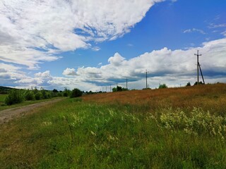 beautiful clouds in the blue sky over the power line in the field