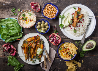 Variety of healthy vegan snacks, gourmet dips. Hummus,  roasted carrots, rice with tempeh in ceramic bowls viewed from above, plant based food