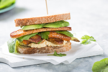 Tempeh and kale sandwich with hummus, spinach and avocado  on table