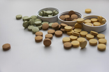 Supplements in containers are scattered on the table close-up. White background. Vitamins and food additives help take care of health, have natural plant components and healthy nutrients.