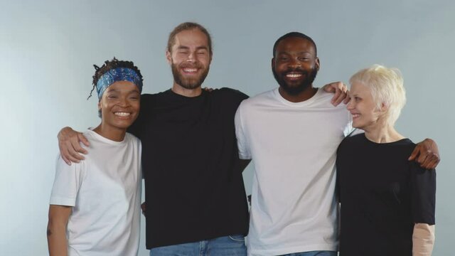 Funny happy Multi-ethnic people look at camera smiling hugging on grey background having fun no racism racial morality society peace matter human slow motion