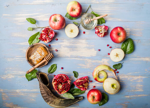 Rosh hashanah  (Hashana) - jewish New Year holiday concept. Traditional symbols: Honey jar and fresh apples with pomegranate and shofar - horn on a blue background. Copy space for text. 