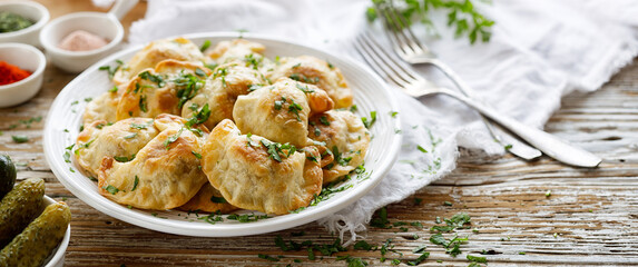 Baked dumplings stuffed with mushrooms and lentils, sprinkled with chopped fresh parsley on a white...