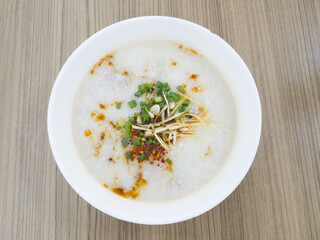 Congee is a type of rice porridge or gruel popular in many Asian countries on the top view with wooden background.