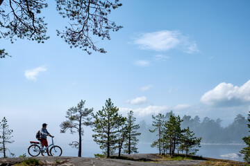 Fototapeta premium Young men riding a bicycle on bike trail at the lake in the morning. Active people spending time outdoors