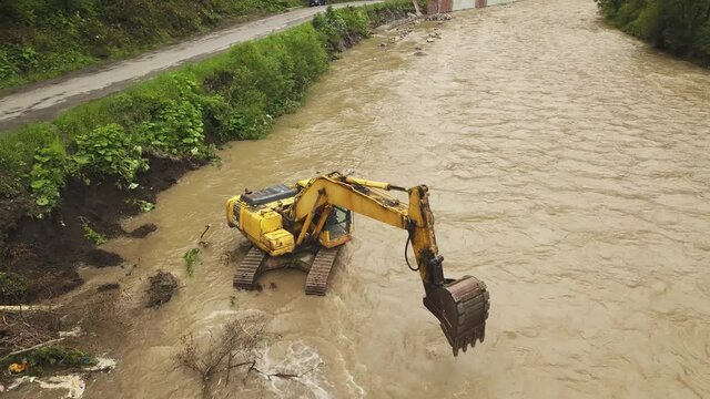 Yellow dredge Excavator working in the mountain river, scooping excavator bucket. Extracting gravel excavated in the river. Hydraulic works to strengthen the mountain road from floods.