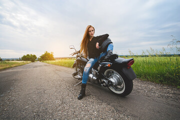 Naklejka na ściany i meble Stylish girl biker posing on a motorcycle.
