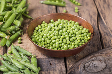 Young fresh green peas on wooden  table viewed from above