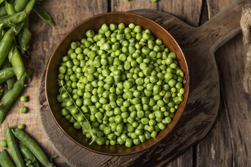 Young fresh green peas on wooden  table viewed from above