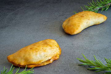 Two homemade freshly baked empanadas pastry with meat filling a gluten-free version of an authentic traditional Spanish Latin America cuisine food on a dark background 