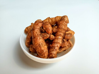 Turmeric or Curcuma longa rhizomes in a bowl, isolated in white background