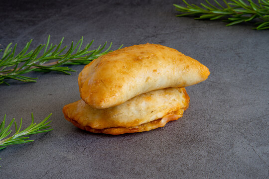 Two homemade freshly baked empanadas pastry with meat filling a gluten-free version of an authentic traditional Spanish Latin America cuisine food on a dark background 