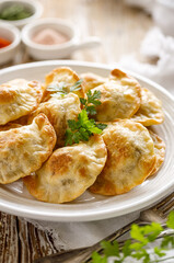 Baked dumplings stuffed with mushrooms and lentils on a white plate on a wooden table, close up view