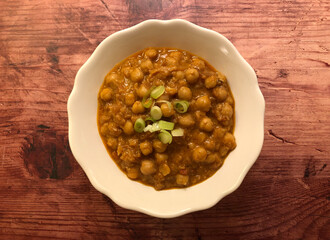 Healthy vegetarian chickpea curry bowl on wooden background.
