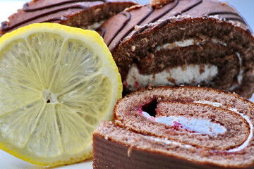 Cherry roll with white, whipped, cream and lemon slice on a white background, close-up