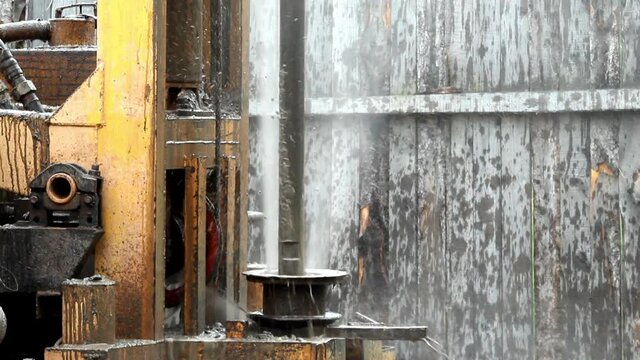 Powerful jet of water and mud comes from the well.Water well drilling.The process of drilling an artesian well.