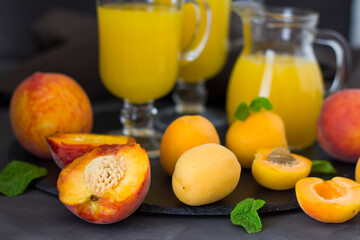 Summer apricot juice. Fresh peach juice. Peaches and apricots with a green leaf on a dark surface. copyspace