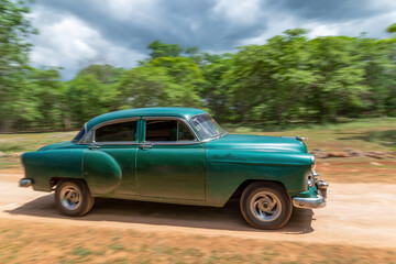 Obraz na płótnie Canvas HAVANA, CUBA - CIRCA 2017: Panning on an American blue classic car in the streets of Havana, transporting tourists. Concept of tourism having fun.