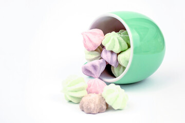 Meringue on a white background. Multi-colored meringues in a green cup on a white background. background