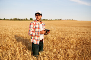 Naklejka na ściany i meble Precision farming. Farmer holding tablet pc, using online data management software at wheat field. Agronomist working with touch computer screen, control, analyse agriculture business. Innovative tech