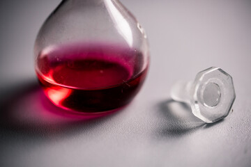 closeup of two conical erlenmeyer flasks with red liquid and a glass plug.