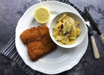 Breaded cod fish, kabeljou with potato salad  and lemon.