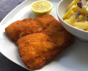 Breaded cod fish, kabeljou with potato salad  and lemon.