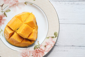 Yellow ripe cut mango on plate, top down.
