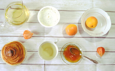 Healthy breakfast on the table with green tea cup, glass teapot, fresh apricots, apricot jam,  twist of bread, skyr. Healthy life style. Food still life. Top view