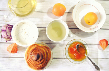 Healthy breakfast on the table with green tea cup, glass teapot, fresh apricots, apricot jam,  twist of bread, skyr. Healthy life style. Food still life. Weight control and diet organic meal.