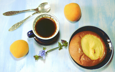 Light vitamin-rich healthy breakfast  on the light blue wooden table  with cheese pastry, chicory caffeine-free drink in blue cup, chicory flower, spoons, apricots 