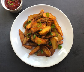 Potato wedges or oven baked potato with ketchup. 