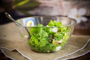 spring salad with arugula, boiled eggs, fresh radish, salad leaves in a glass bowl