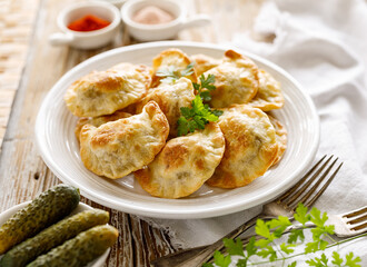 Baked dumplings stuffed with mushrooms and lentils on a white plate on a wooden table, close up view