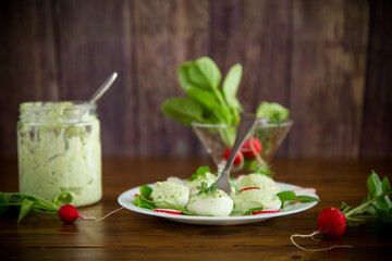 boiled stuffed eggs with green cheese filling with arugula leaves and radish