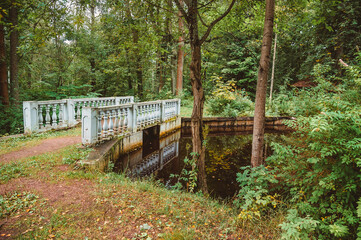 A small bridge over a creek in the woods. The architecture of the 19th century in the classicism style.