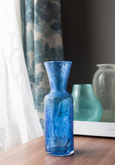 Mid-century modern glass vases in blue and green interior, before the window