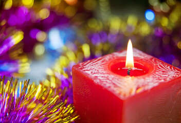 Burning red candle on the blur background close-up