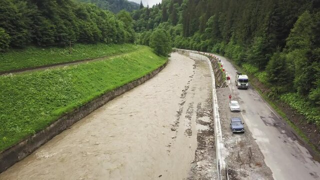 aerial flight over the mountain river black yew in Ukraine Carpathians, near the road on which a trucker rides