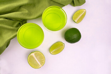 Green drink with lime on a white background. Flat lay