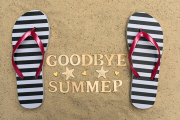 Naklejka premium Flip flops and the inscription goodbye summer on the sand.