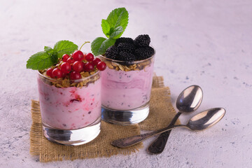 Two glasses of yogurt with fresh mulberries and red currants.