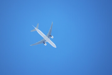 White airplane flying in the clear blue sky, bottom view. Two-engine commercial plane during taking off