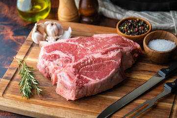 fresh T-bone steak on wooden cutting board